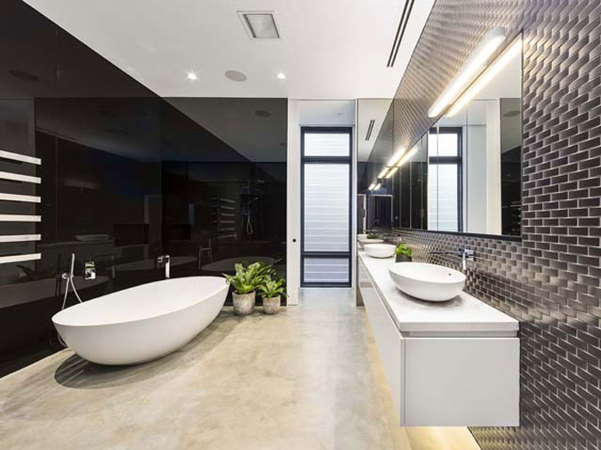 Designer sbathroom with black walls, a free standing bathtub and basin sinks